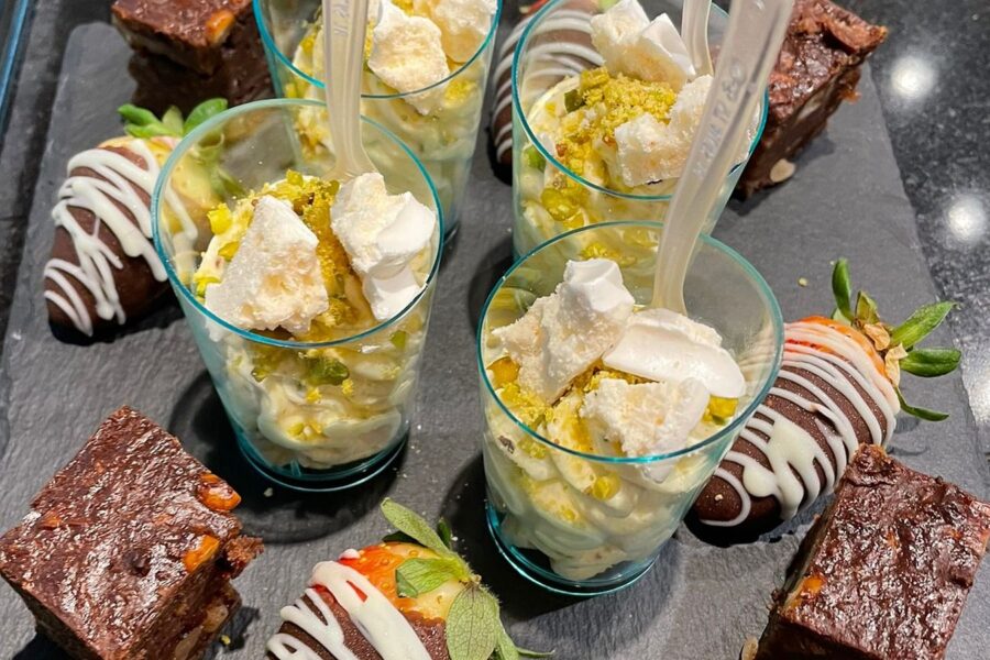 Brownies, chocolate-dipped strawberries and dessert glasses on slate